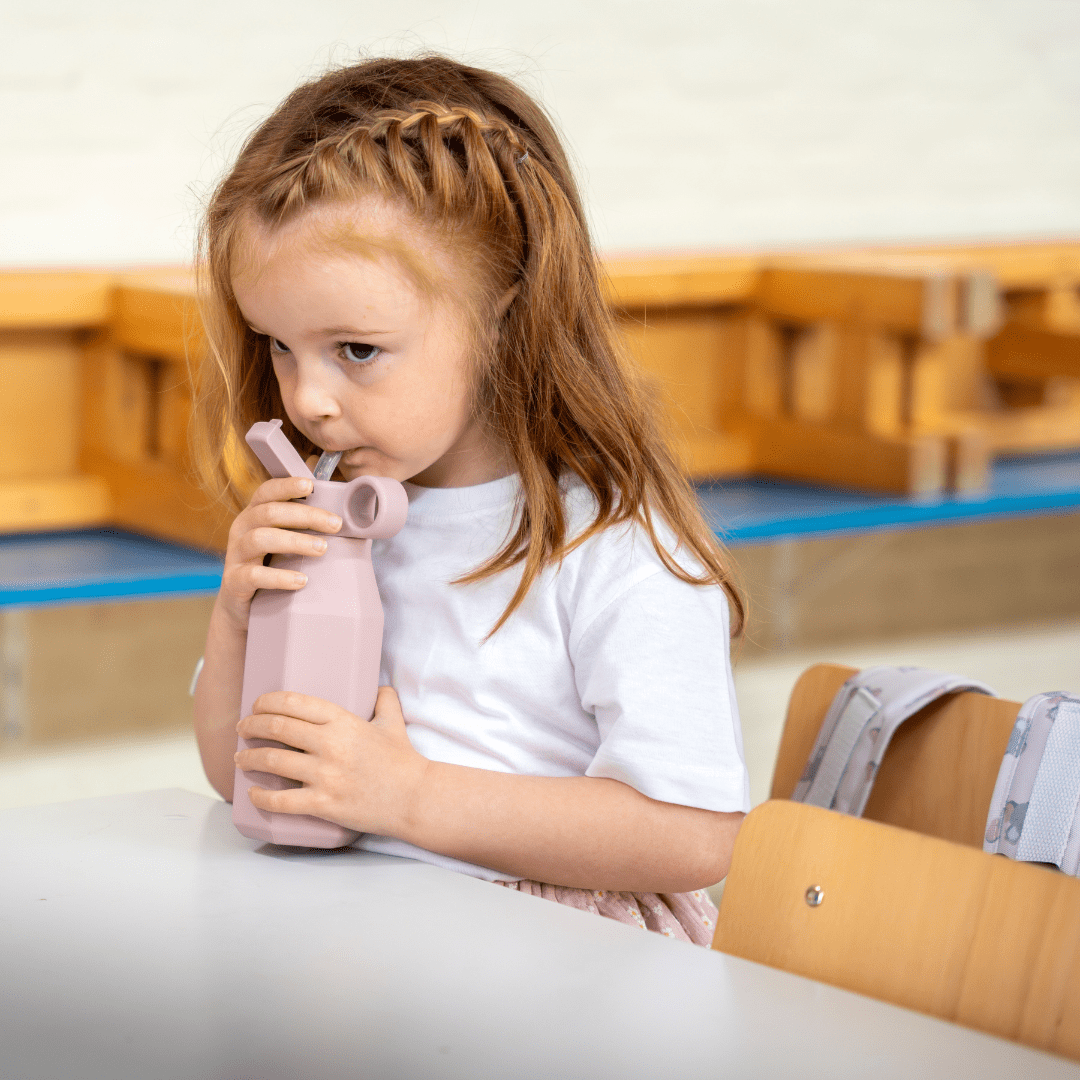 De roze drinkfles in gebruik door een kindje.